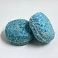 Detox shampoo bar and conditioner bars sitting on a white table with a window in the background