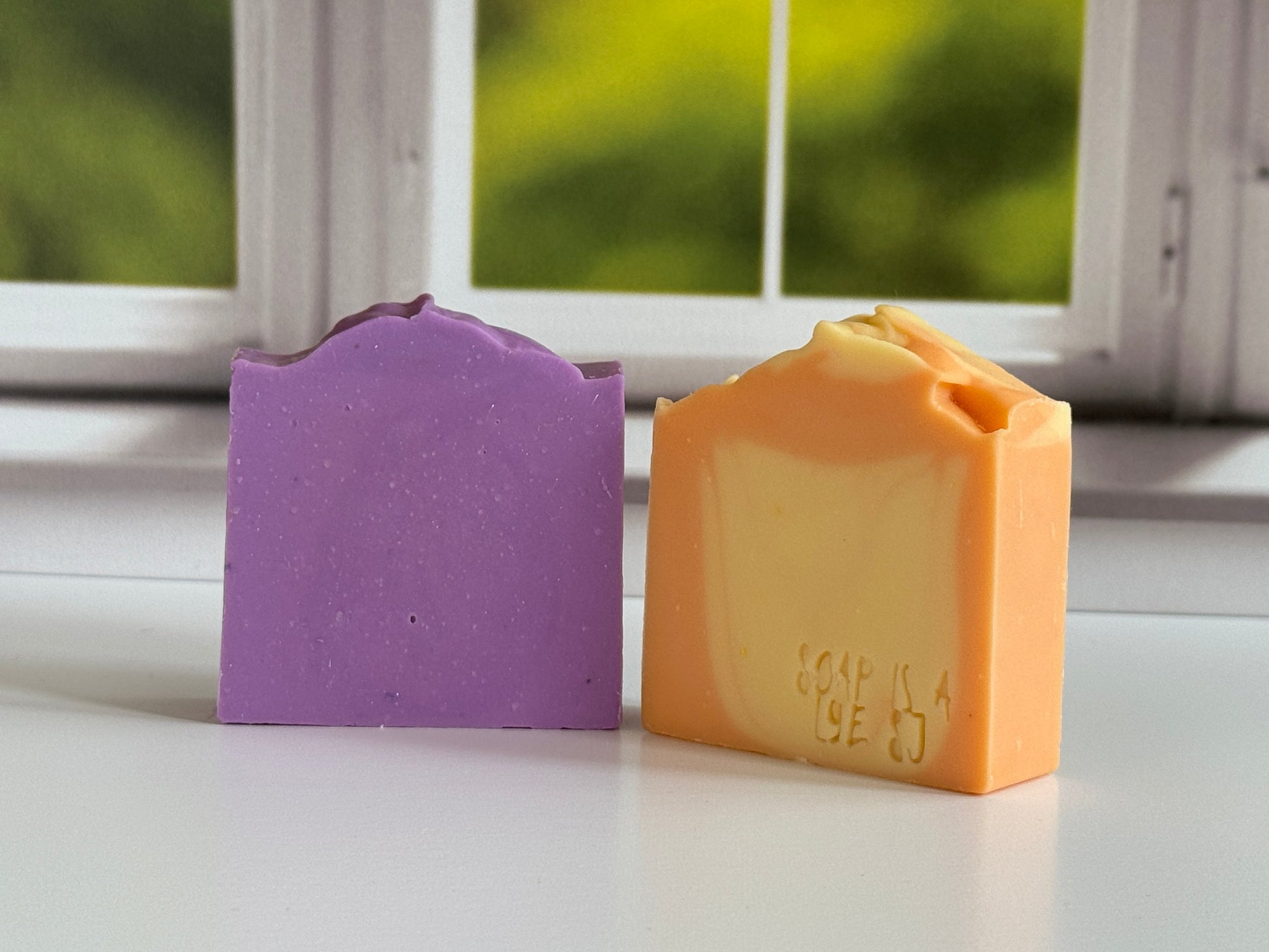 Close-up of Energy Orange and yellow artisan soap displayed with an purple natural soap bar.