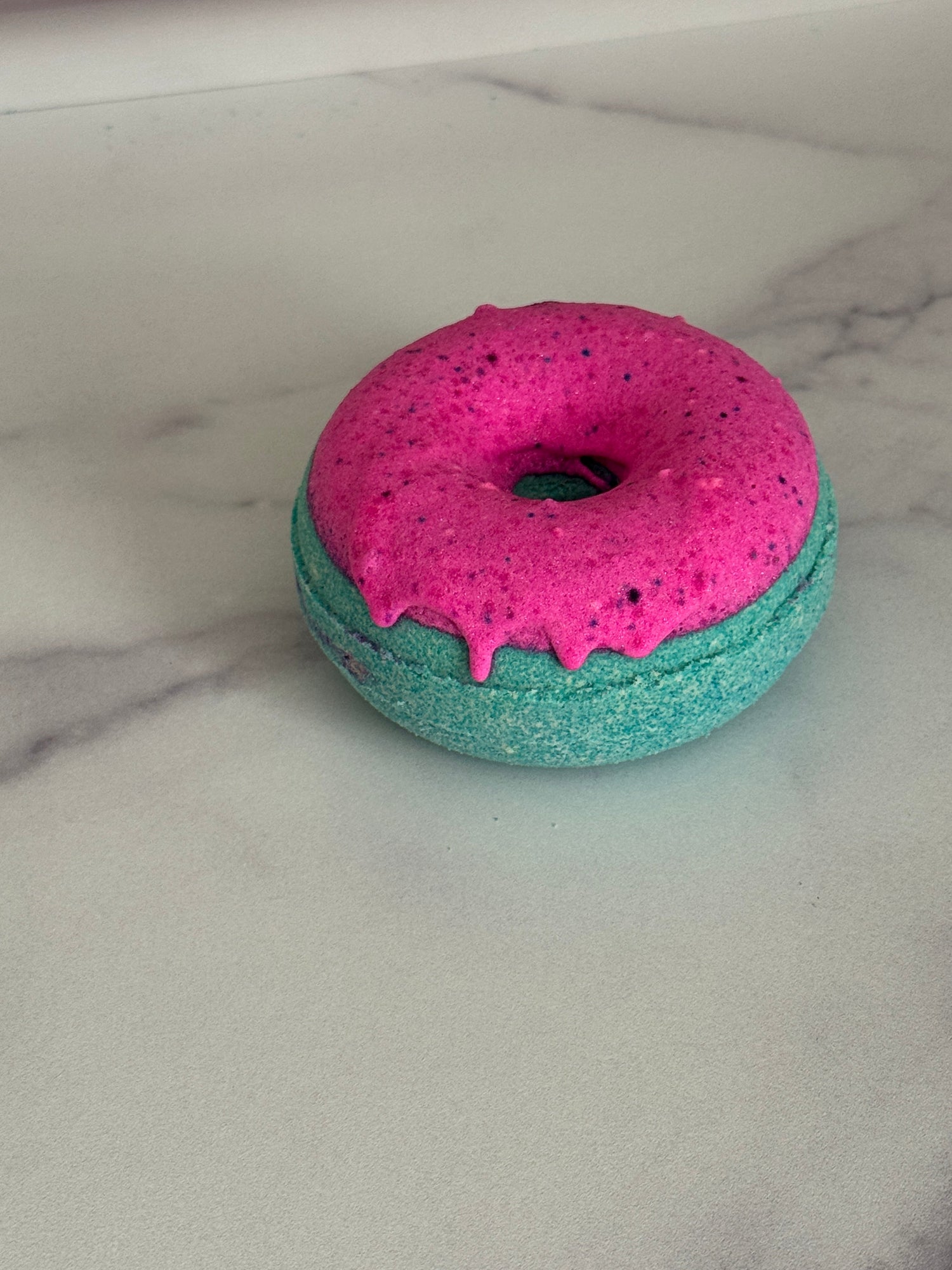 Donut bath bomb that is green with pink frosting