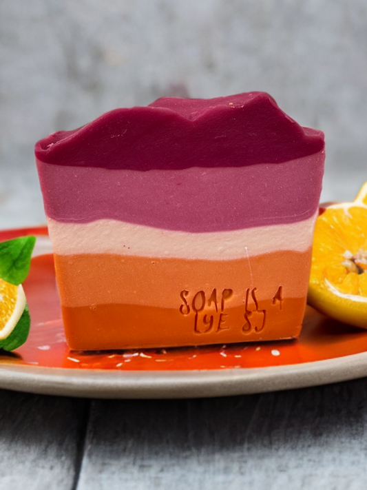 Lesbian Pride soap sitting on a plate surrounded by a lemon and lime.