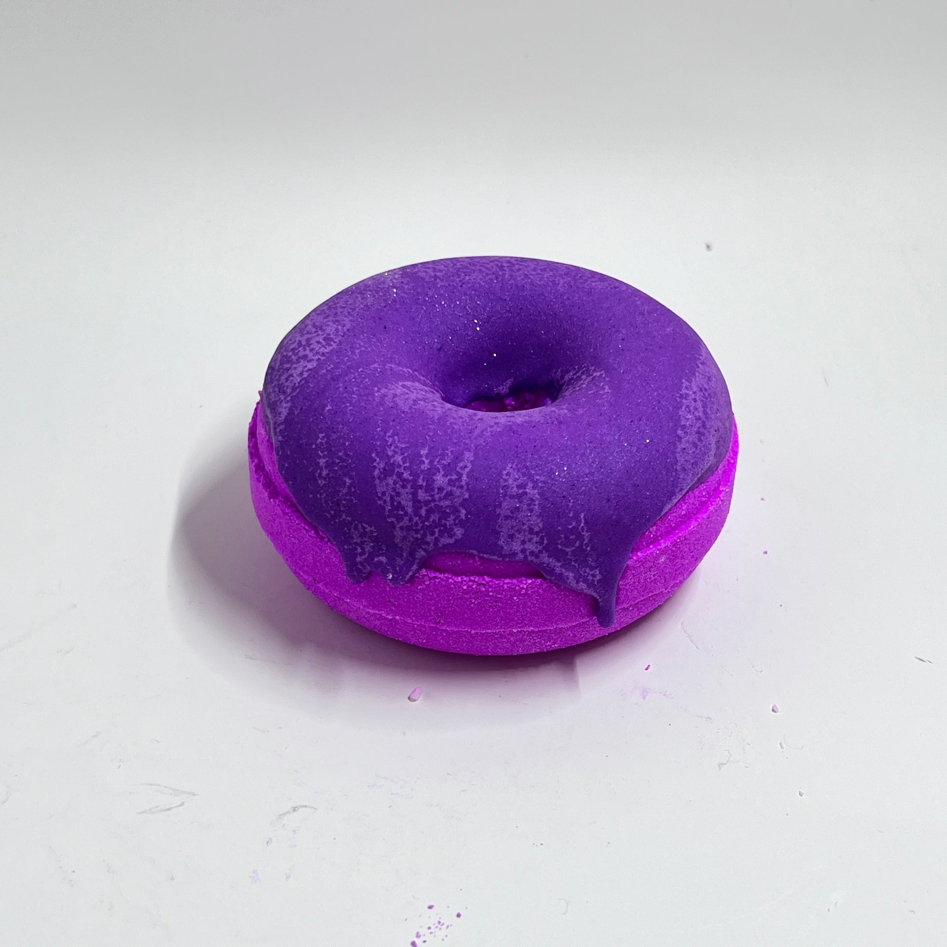 pink donut bath bomb with purple frosting that smells like watermelon candy. This bath bomb will make your bath water pink and purple