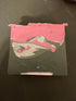 A rectangular bar of soap with a swirled pattern of pink, dark gray, and white, resting on a dark surface.