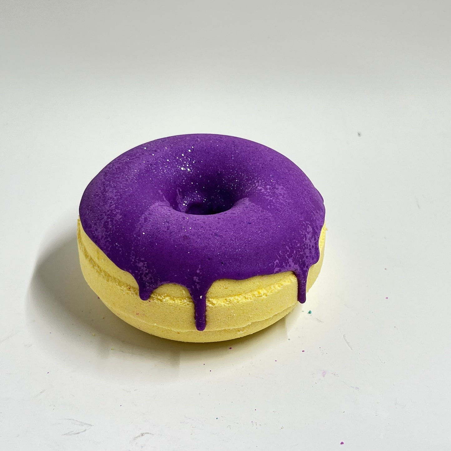 Yellow Donut bath bomb with purple frosting. Fragranced with Hibiscus and honey, frosting is made out of cocoa butter